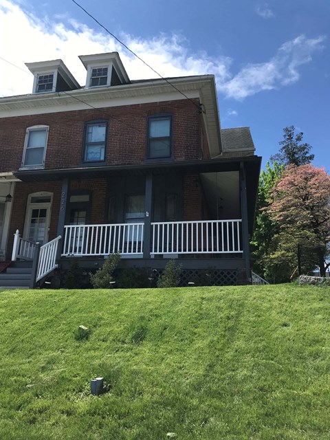 A red brick house with a white porch.