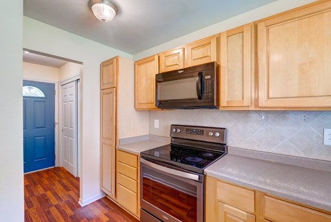 A kitchen with wooden cabinets and a black microwave.