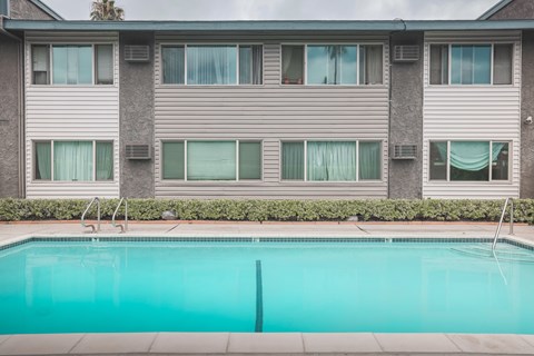 A swimming pool in front of a grey apartment building.