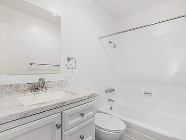 A white bathroom with a toilet, sink, and bathtub.