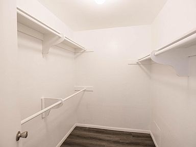 A white hallway with a wooden floor and a door.
