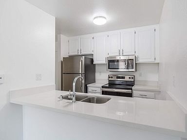 A kitchen with white cabinets and appliances.