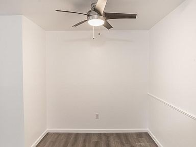 A room with a ceiling fan and wooden flooring.