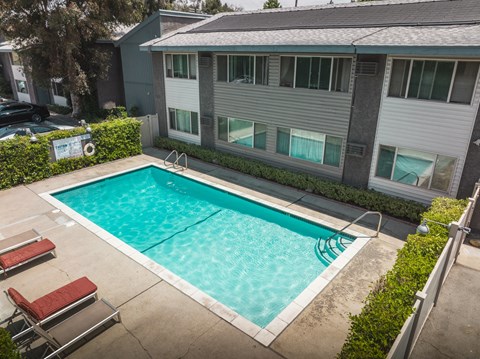 A small pool in a backyard with a building in the background.