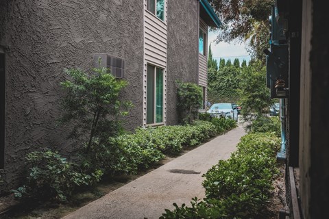 A narrow alley with a building on the left and a car parked on the right.
