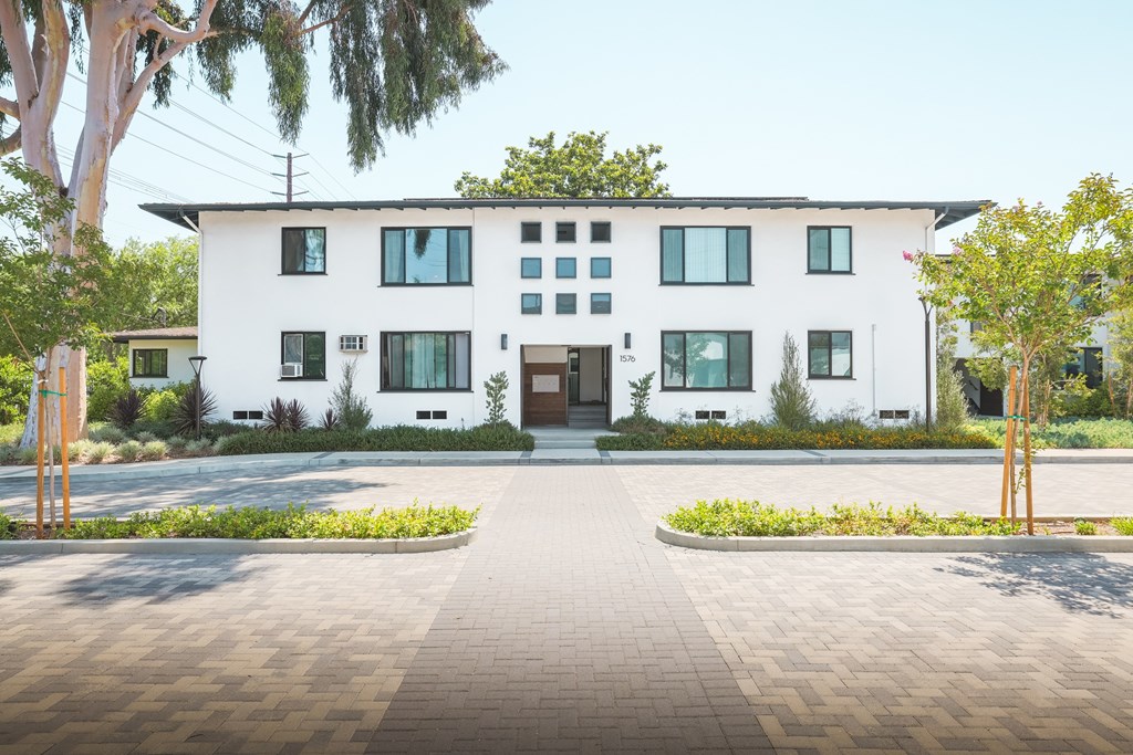 A white modern house with a grey walkway in front.