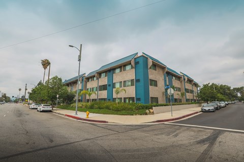 A street view of a blue building with cars parked in front.