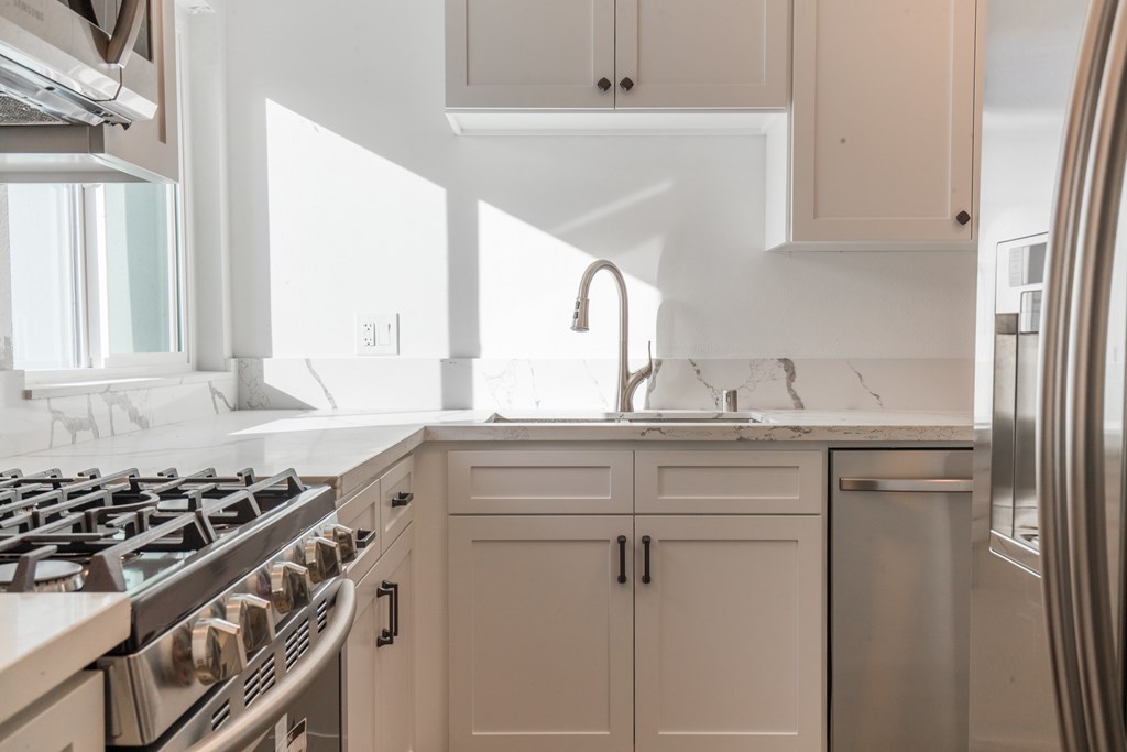 A modern kitchen with a stove, sink, and cabinets.