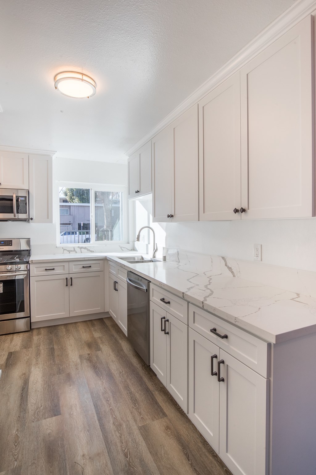 A kitchen with white cabinets and a marble countertop.