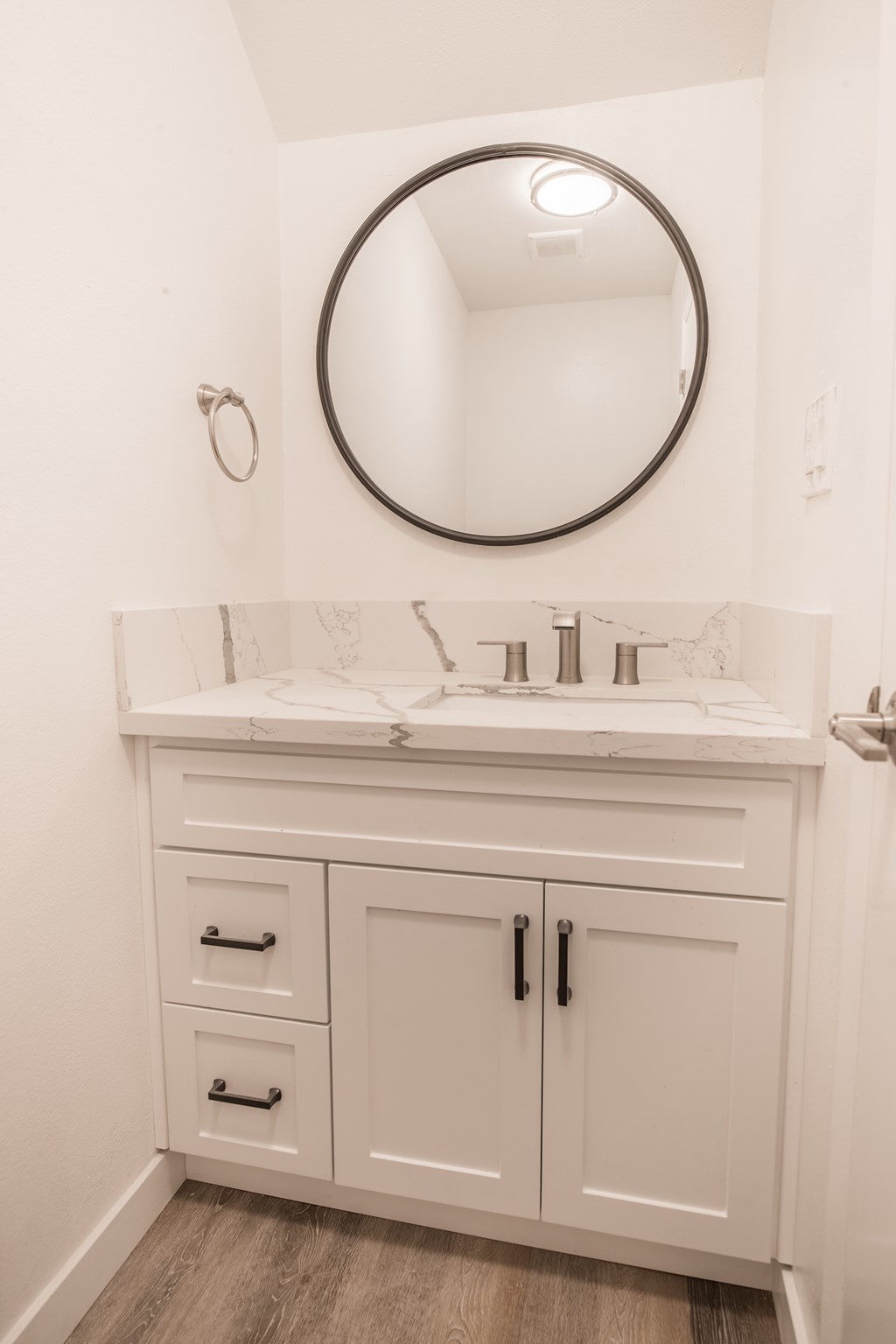 A bathroom with a white sink and a round mirror.