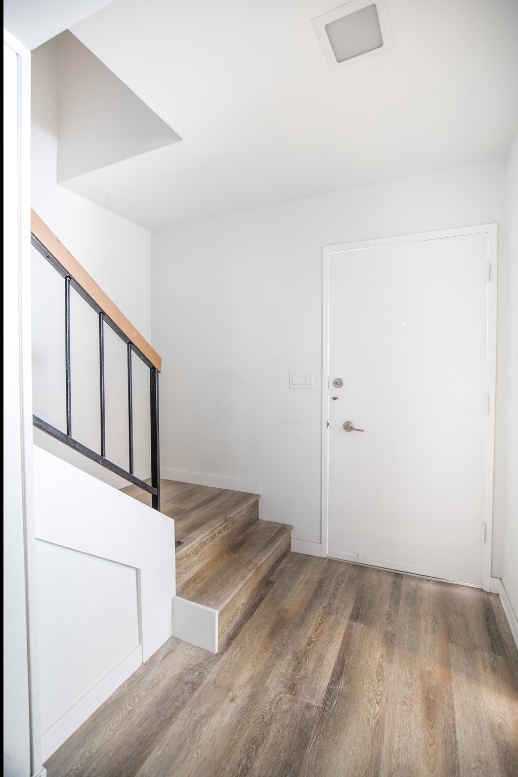 A white door is on the right side of a staircase.