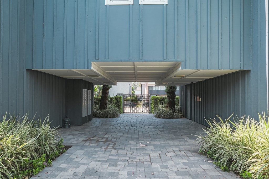 A long hallway with a brick floor and a metal gate at the end.