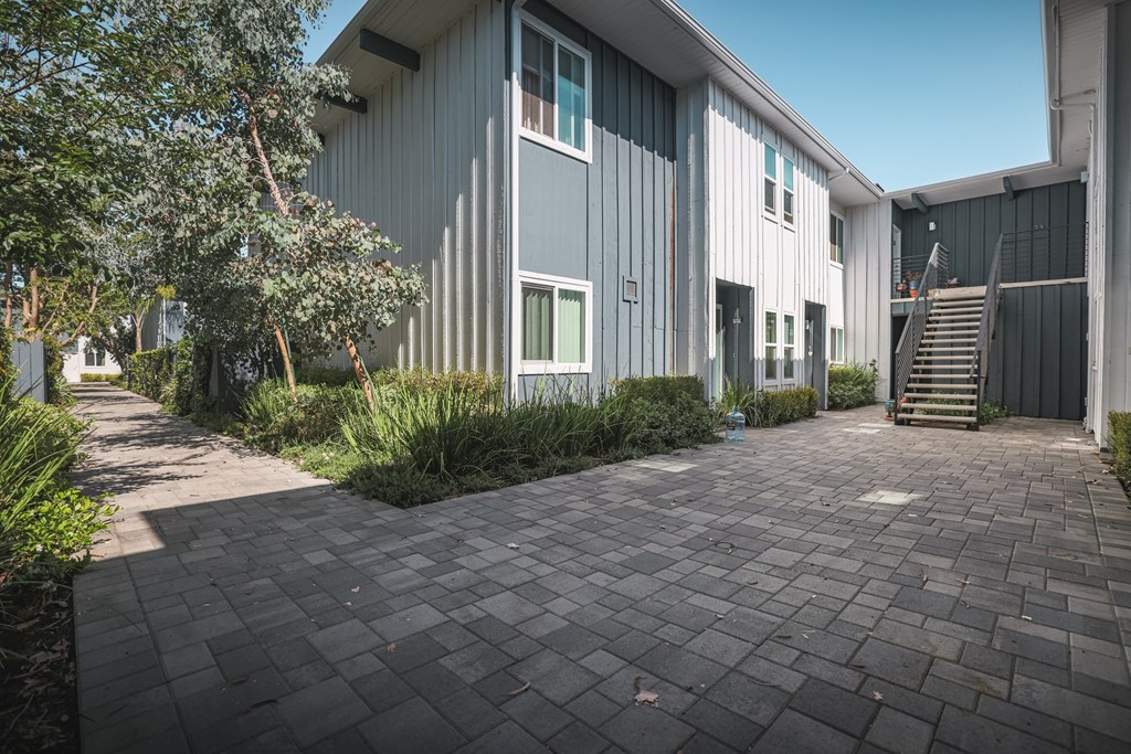 A modern building with a grey exterior and a stone pathway leading to the entrance.