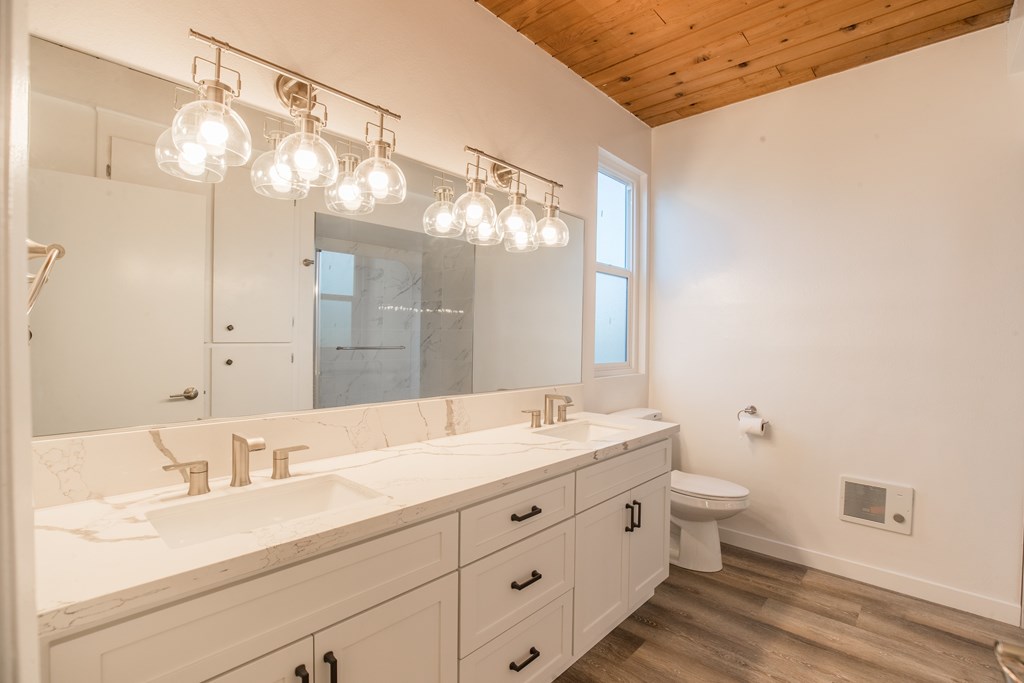 A bathroom with a marble countertop and a wooden ceiling.
