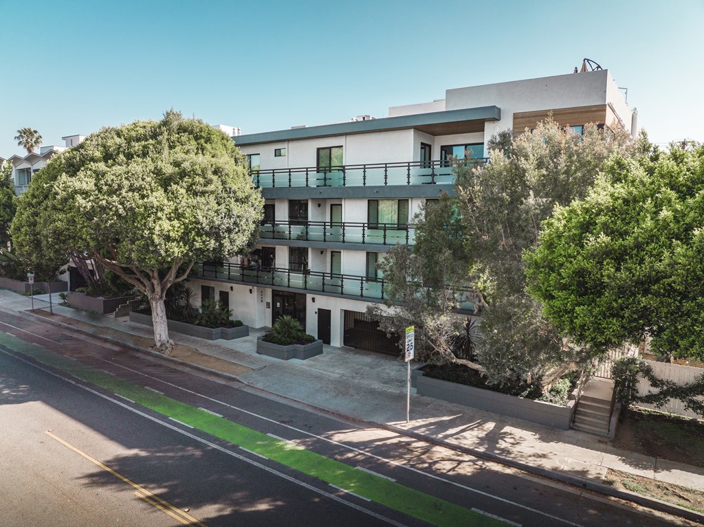 A street view of a residential area with apartment buildings and trees.