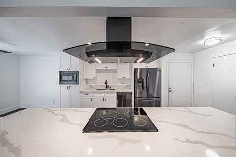 A modern kitchen with a large island and stove top.