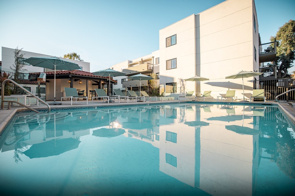 A large swimming pool in front of a building with a sunny day.