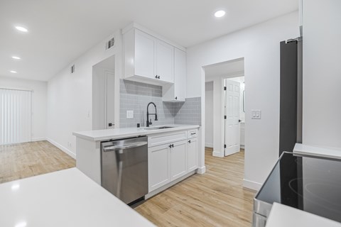 A modern kitchen with white cabinets and stainless steel appliances.