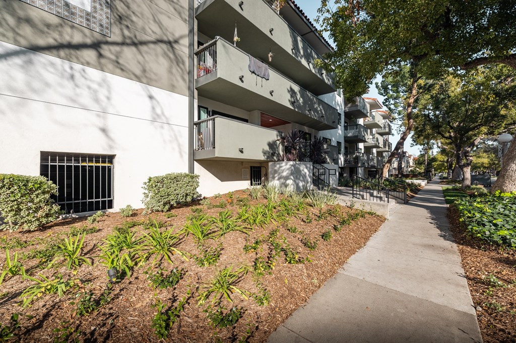 A white building with a balcony and a small garden in front.