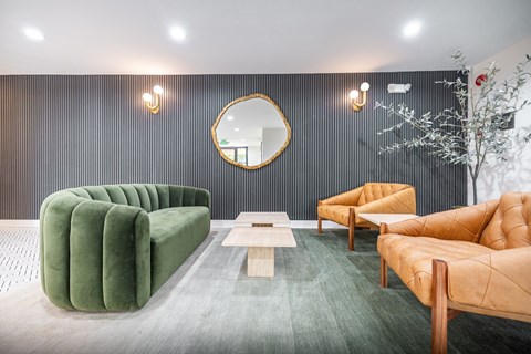 A modern living room with a green sofa, a wooden coffee table, and a round mirror on the wall.