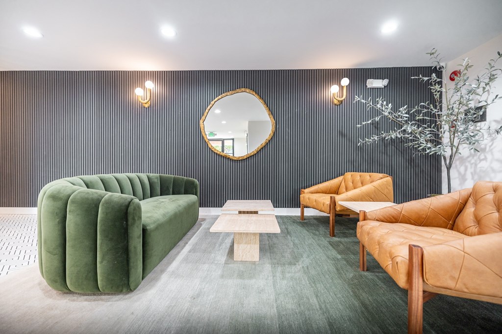A modern living room with a green sofa, a wooden coffee table, and a round mirror on the wall.