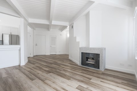 A spacious room with a fireplace and wooden flooring.