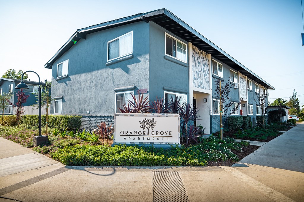 A grey building with a sign that says "Orange Grove Apartments".