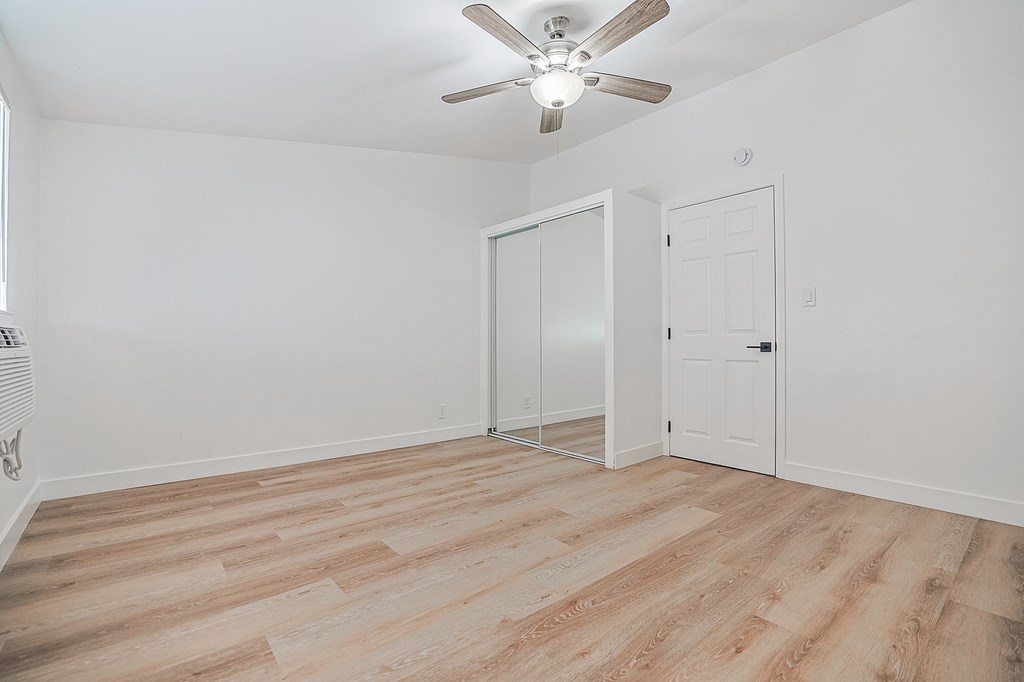 A room with a ceiling fan and a door with a glass panel.