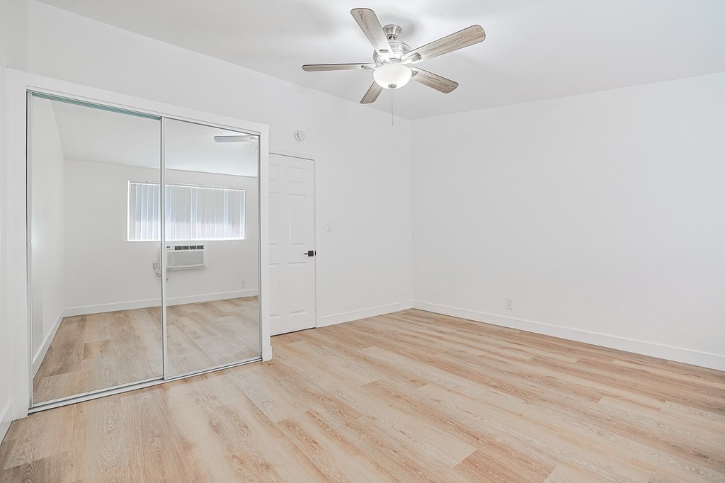 A room with a ceiling fan and a sliding glass door.