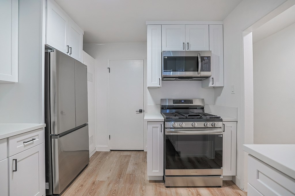 A kitchen with white cabinets and appliances.