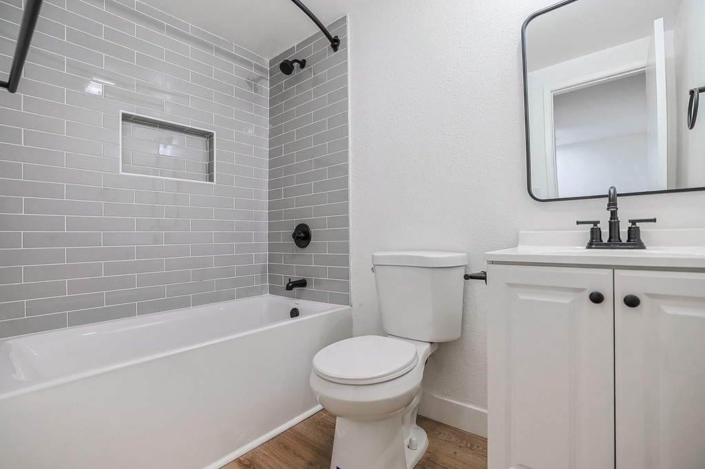 A white toilet sits next to a white bathtub in a bathroom.