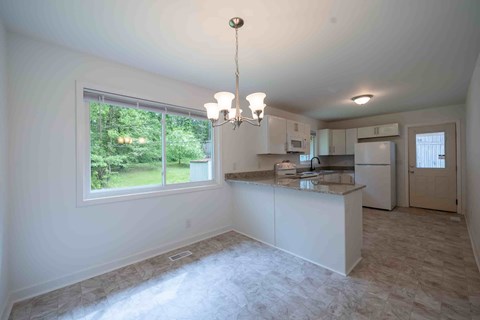 A kitchen with white cabinets and a large window.