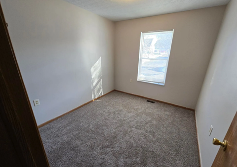 A room with a carpeted floor and a window showing a snowy scene outside.
