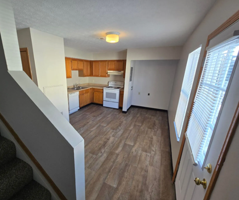 A kitchen with wooden cabinets and a white stove top oven.