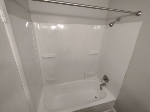 A white bathroom with a white tub and a white shower curtain.
