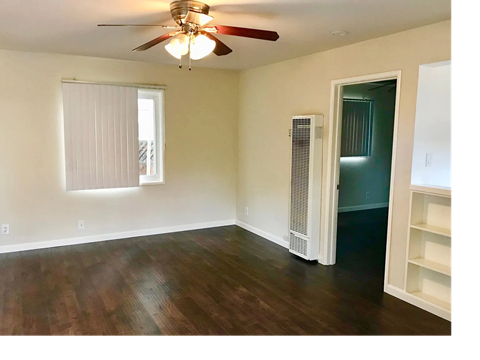 A room with a ceiling fan and a window with blinds.