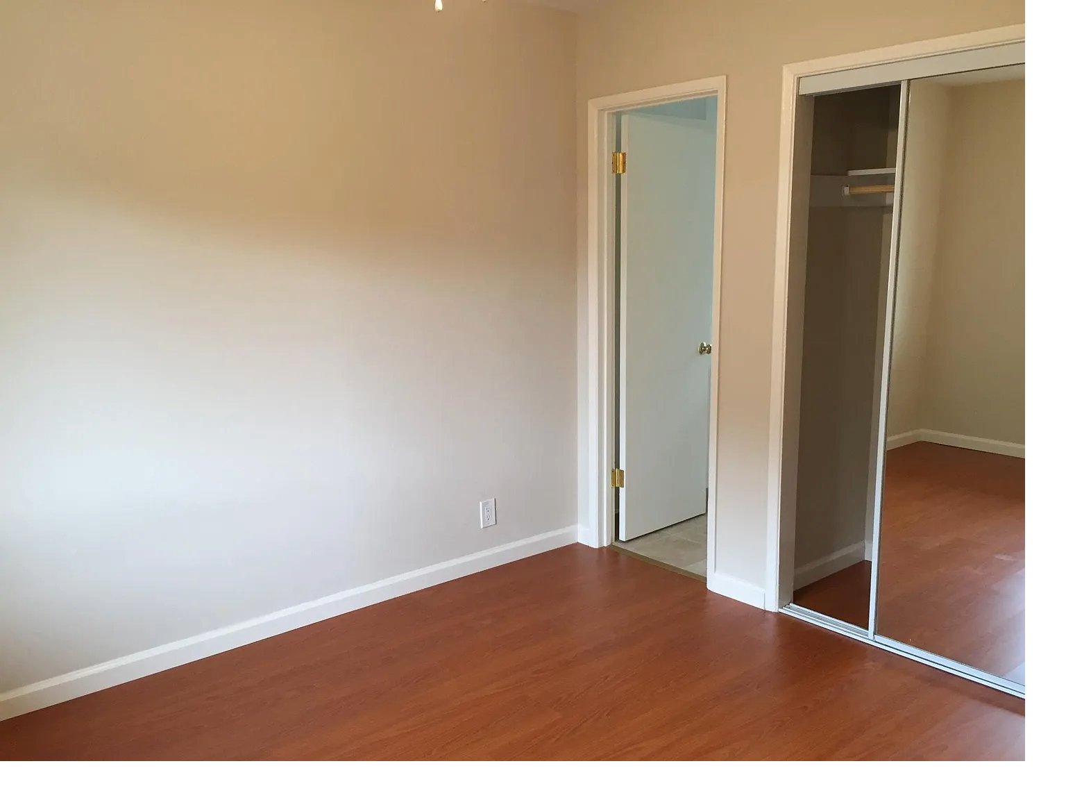A room with a white door and a mirror on the wall.