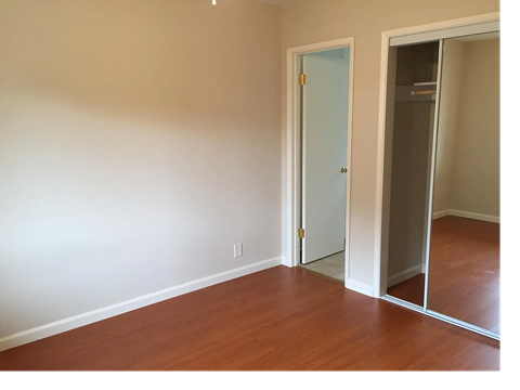 A room with a white door and a mirror on the wall.