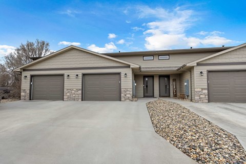 A house with a stone pathway leading to the garage doors.