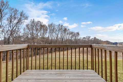 A wooden deck overlooks a grassy field.