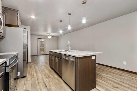 A kitchen with a white counter top and wooden floors.