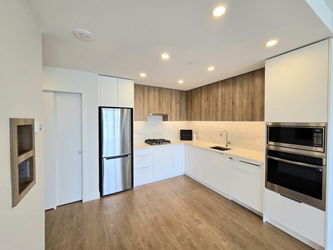 A modern kitchen with white cabinets and stainless steel appliances.