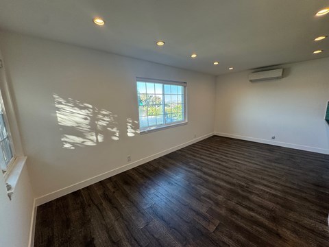 A room with wooden flooring and a window letting in sunlight.