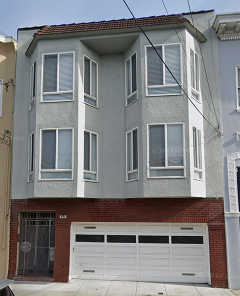 A two-story building with a garage door and a brick wall.