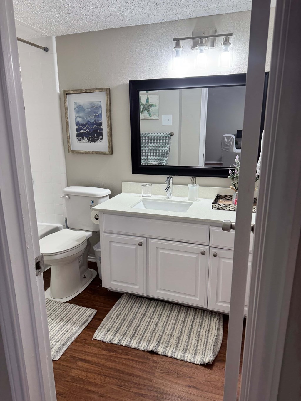 A white bathroom with a toilet, sink, and mirror.