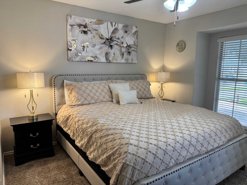 A bedroom with a large bed and a painting above it.