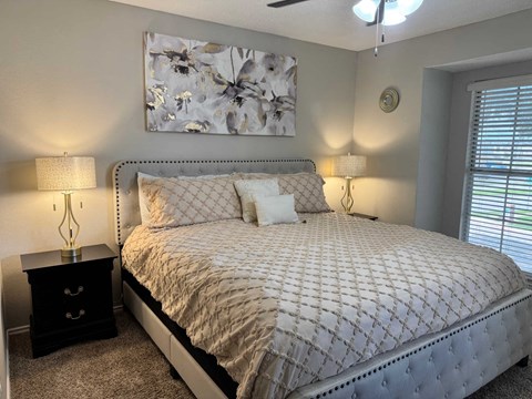A bedroom with a large bed and a painting above it.