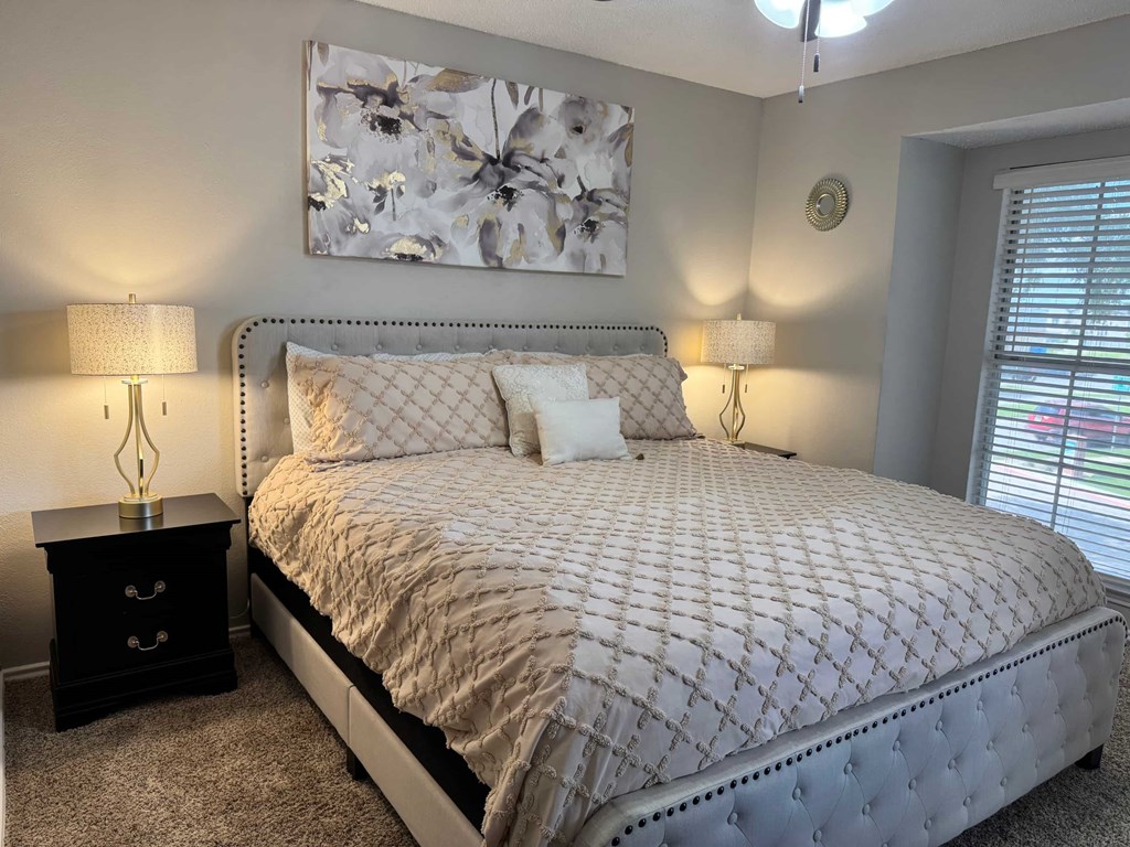 A bed with a grey comforter and a white pillow is in the center of the image.