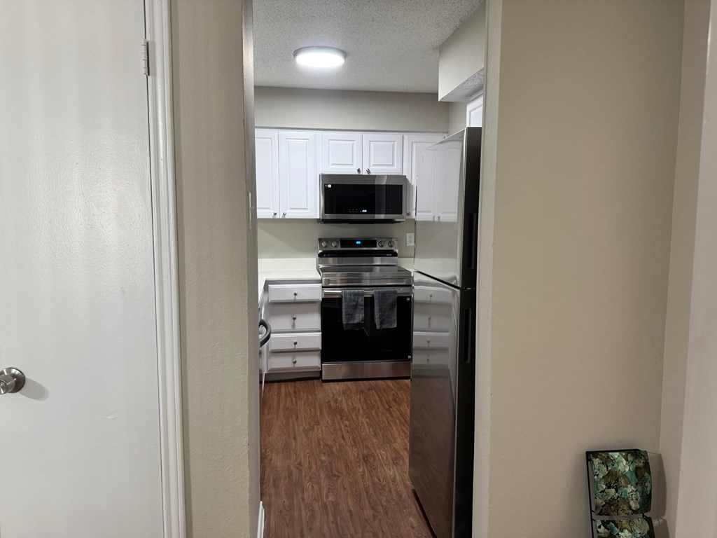 A kitchen with a black fridge and white cabinets.