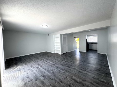 A spacious room with wooden flooring and white walls.